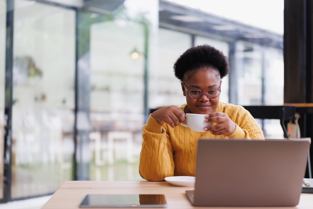 Teacher drinking coffee while ding research on her laptop